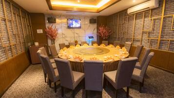 A conference room with a round table, chairs, and a television screen.