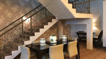 Un área de comedor con una escalera, alfombra de estampado de cebra y barandilla de metal.