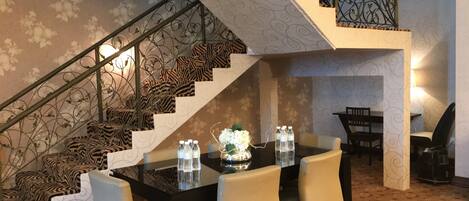 A dining area with a staircase featuring a zebra print carpet and metal railing.