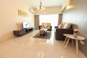 A modern living room with a flat-screen TV, a sofa, a coffee table, and a small side table with a vase.