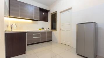 A modern kitchen with dark cabinets, a stainless steel refrigerator, and a white tiled floor.