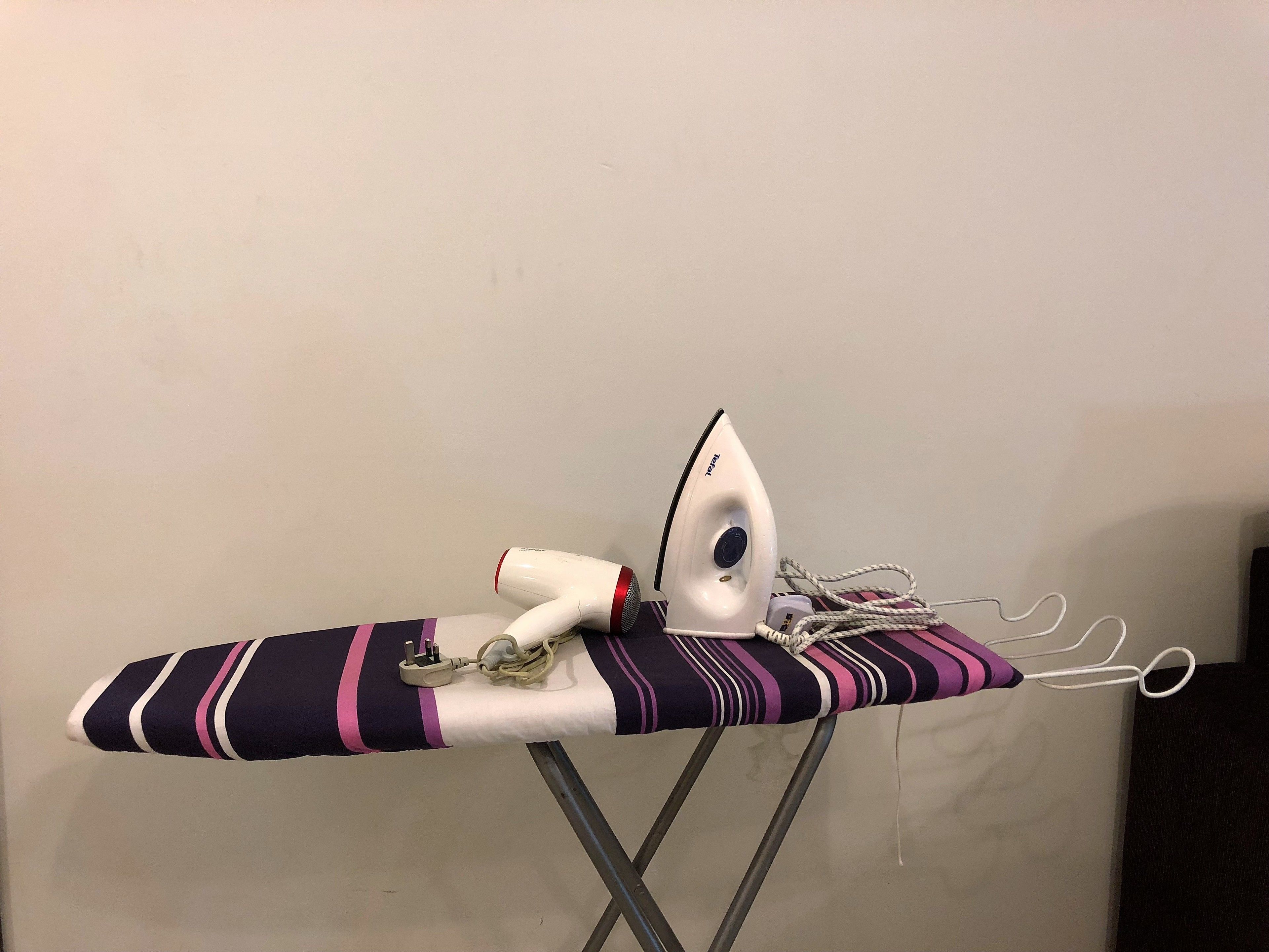 An ironing board with an iron and a power cord.