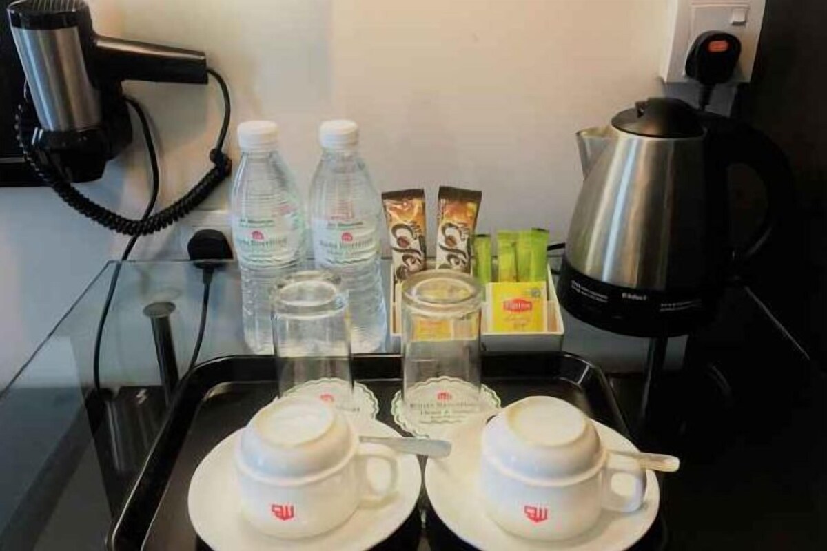 A tray with two cups, two bottles of water, a glass, and a box of tea bags.