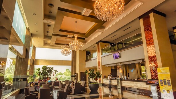 Vestíbulo de hotel con recepción, zona de estar y grandes candelabros.