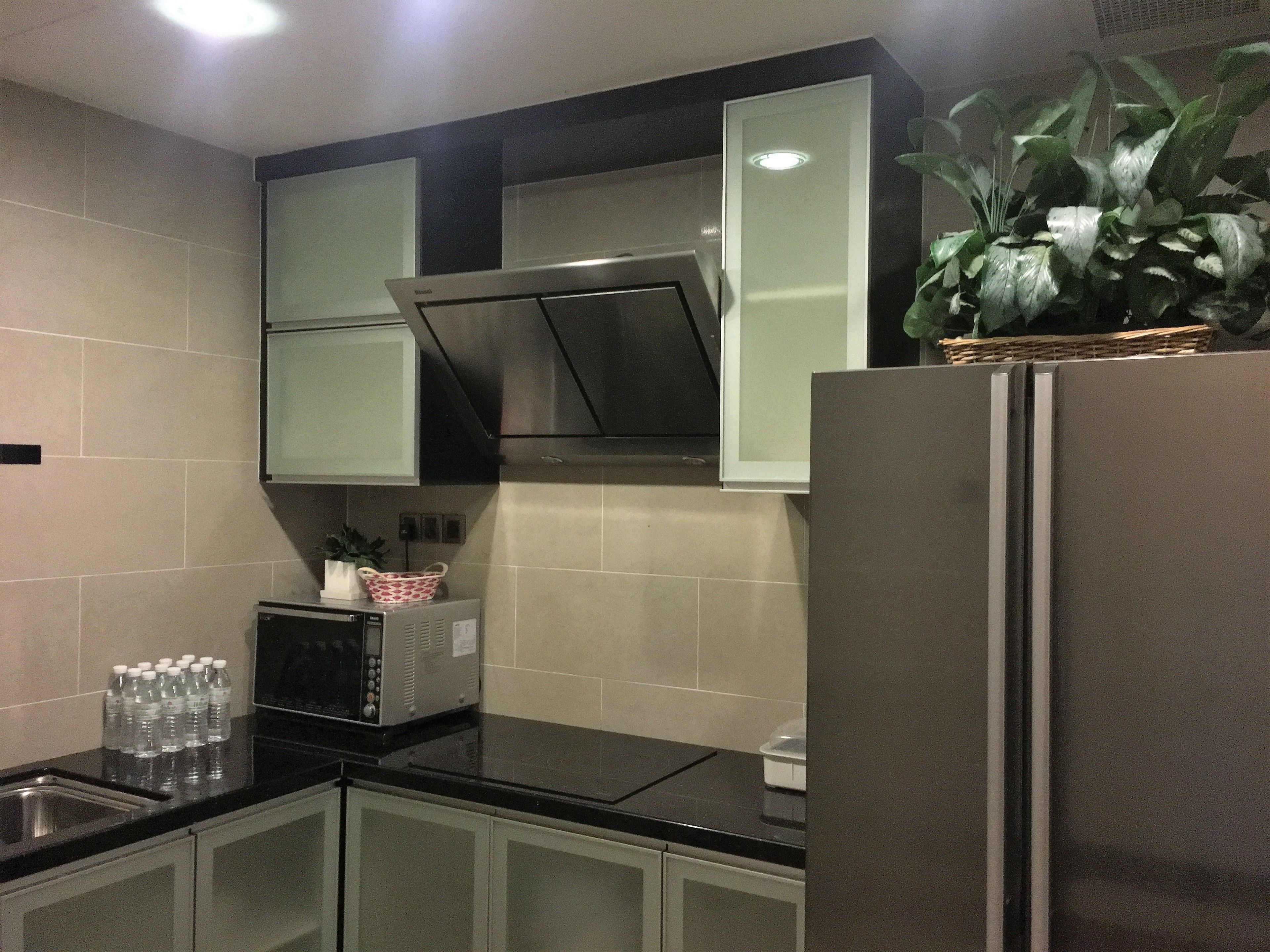 A kitchen with a refrigerator, microwave, and cabinets.