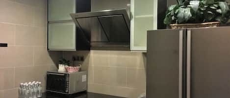 A kitchen with a refrigerator, microwave, and cabinets.