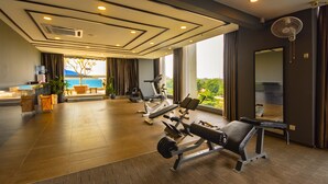 Un gimnasio con equipo de ejercicio, un ventanal con vistas y un ventilador de techo.