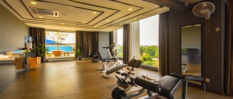 A gym with exercise equipment, a large window with a view, and a ceiling fan.