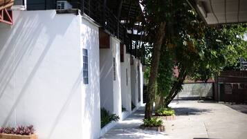 A white building with a covered walkway and a tree in the foreground.