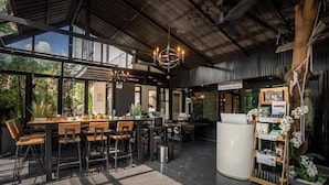 A modern dining area with a large wooden table and chairs, a chandelier, and a display of flowers. - The Nimman Hotel (Chiang Mai)