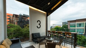 A modern balcony with a sofa, chairs, and a table. A large number '3' is visible on the wall. - The Nimman Hotel (Chiang Mai)