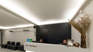 A reception area with a white reception desk, black wall, and seating area. - The Nimman Hotel (Chiang Mai)