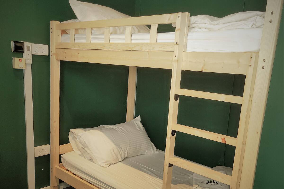 A bunk bed with a mattress, pillows, and a wooden frame.