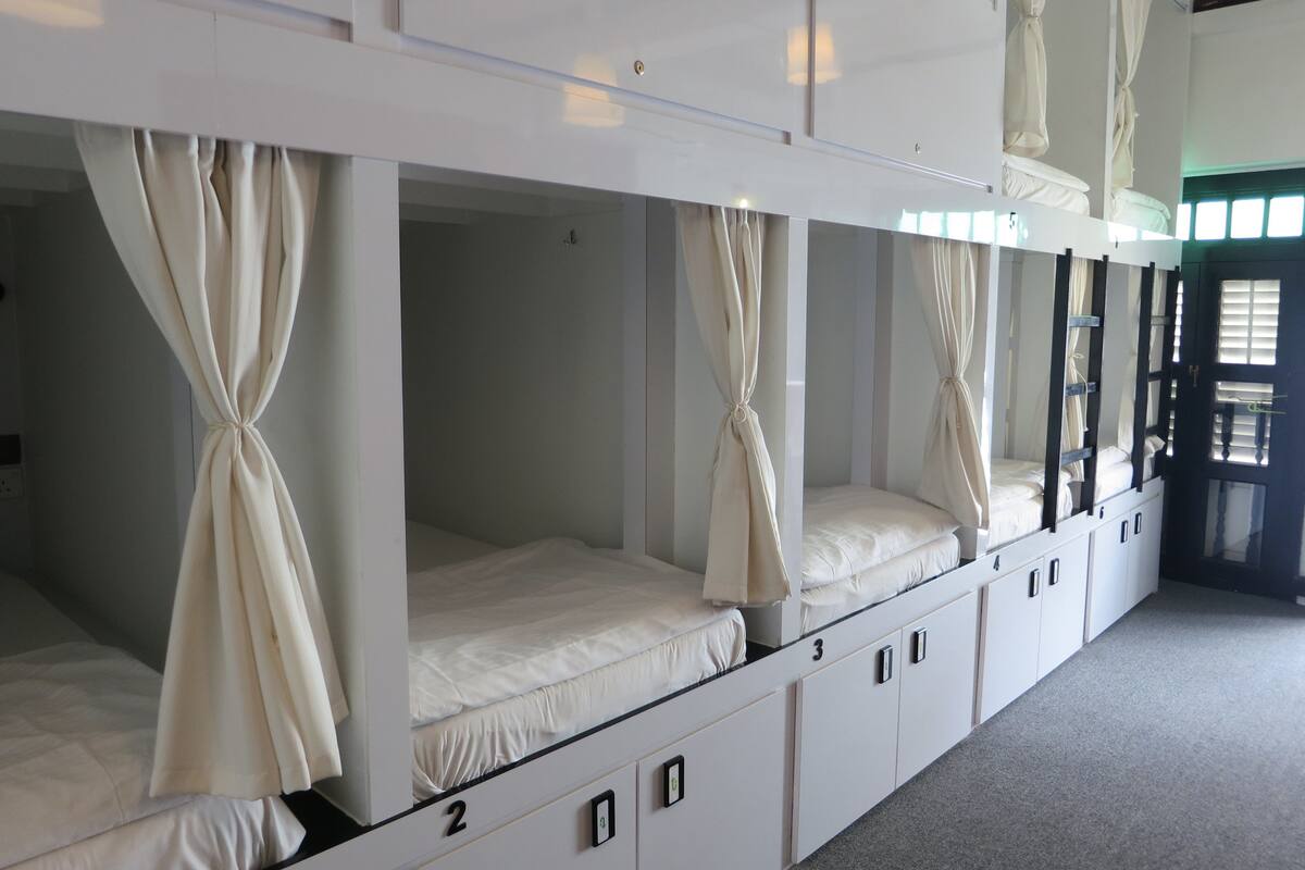 A row of bunk beds with numbers on the side, each with a canopy.