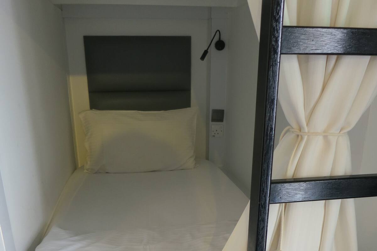 A bunk bed with a headboard, a pillow, and a curtain.
