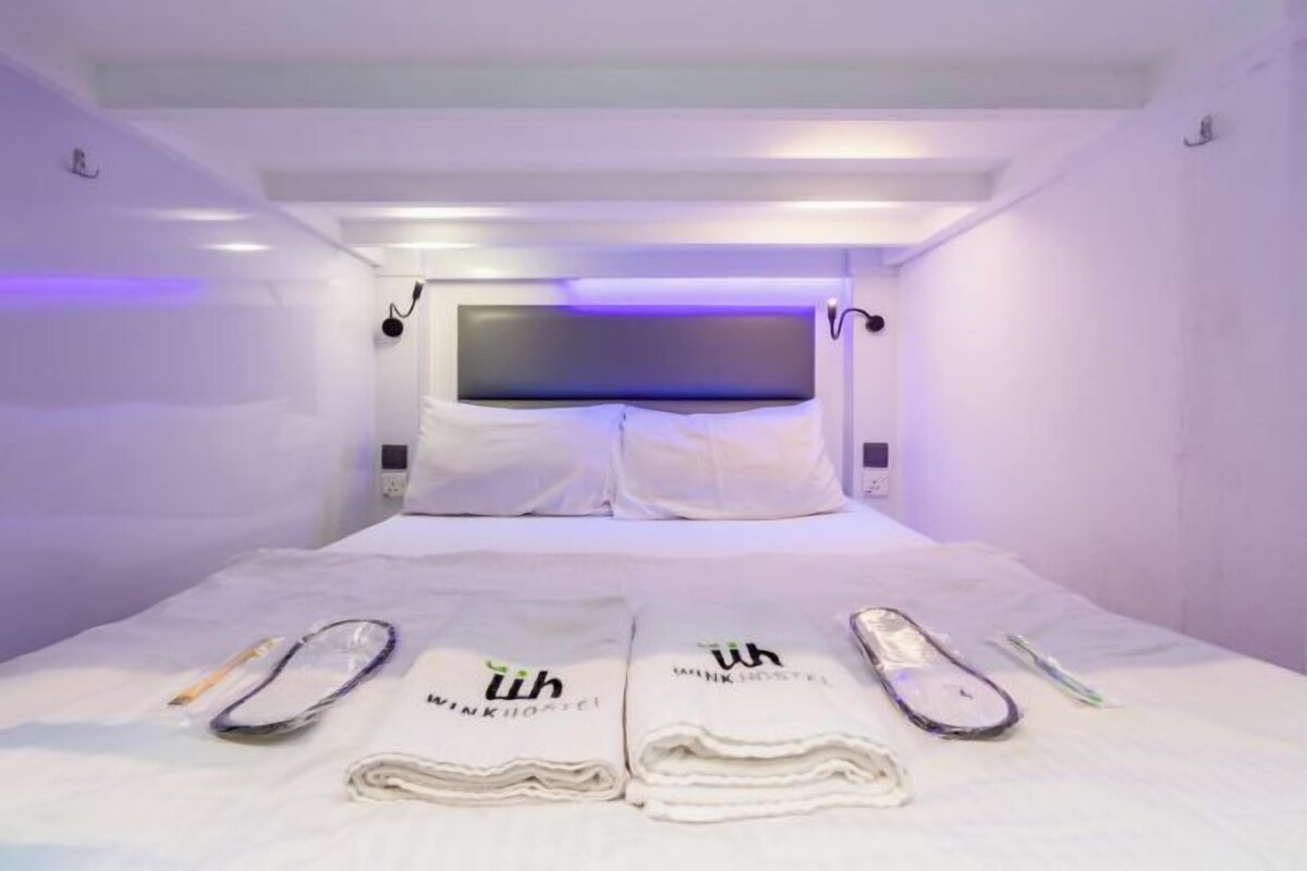 A hotel room with a bed, white linens, a headboard, and a flat-screen TV.