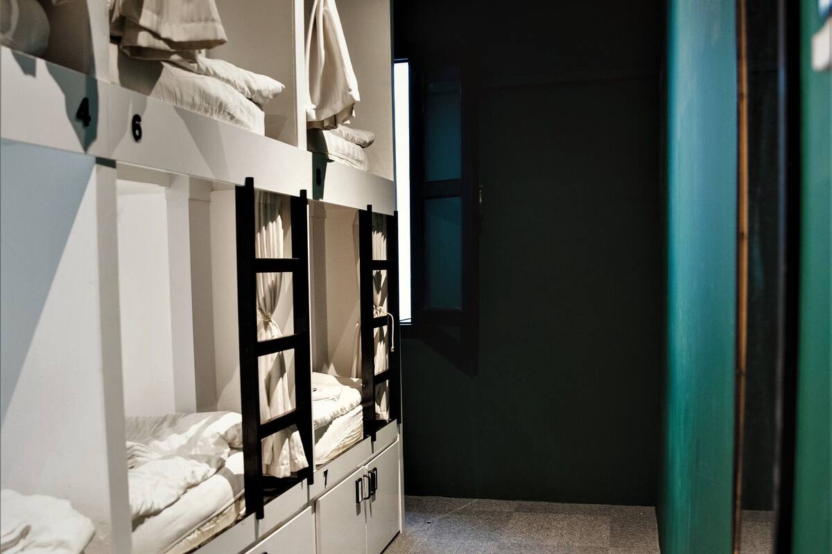 A dormitory room with bunk beds, storage cabinets, and a window.