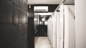 Een gang met een rij witte kasten en een airconditioningunit aan het plafond.