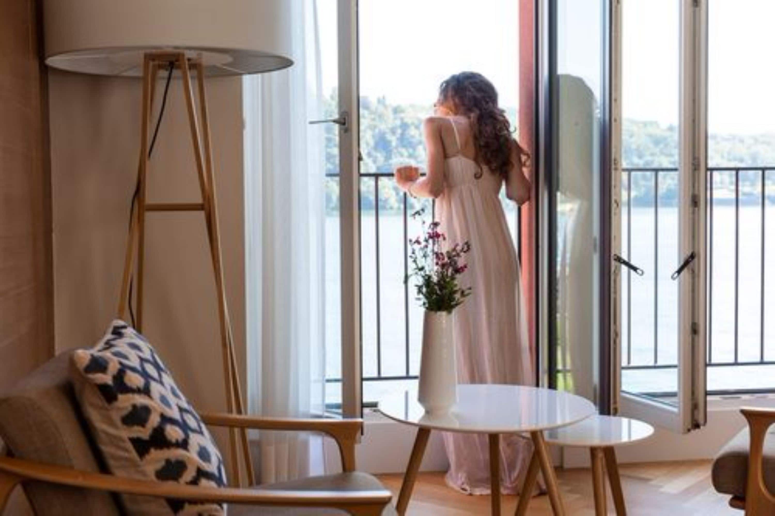 A room with a large window, a standing lamp, a white table, and a chair.