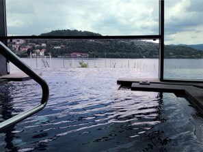 A view from a window overlooking a lake with a dock and buildings in the background. - Hotel de Charme Laveno -Luxury all Inclusive (Laveno Mombello)