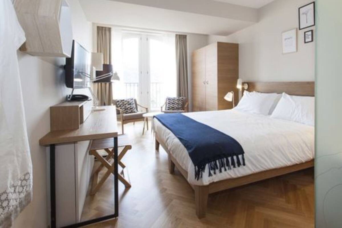 Une chambre d’hôtel comprenant un lit, un bureau, une chaise, une télévision et une armoire.