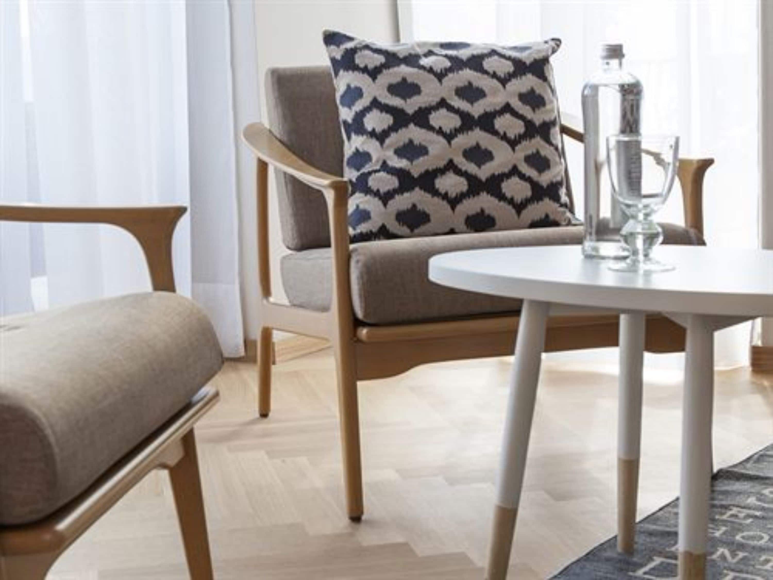 A modern room with a wooden chair, a round white table, and a patterned pillow.
