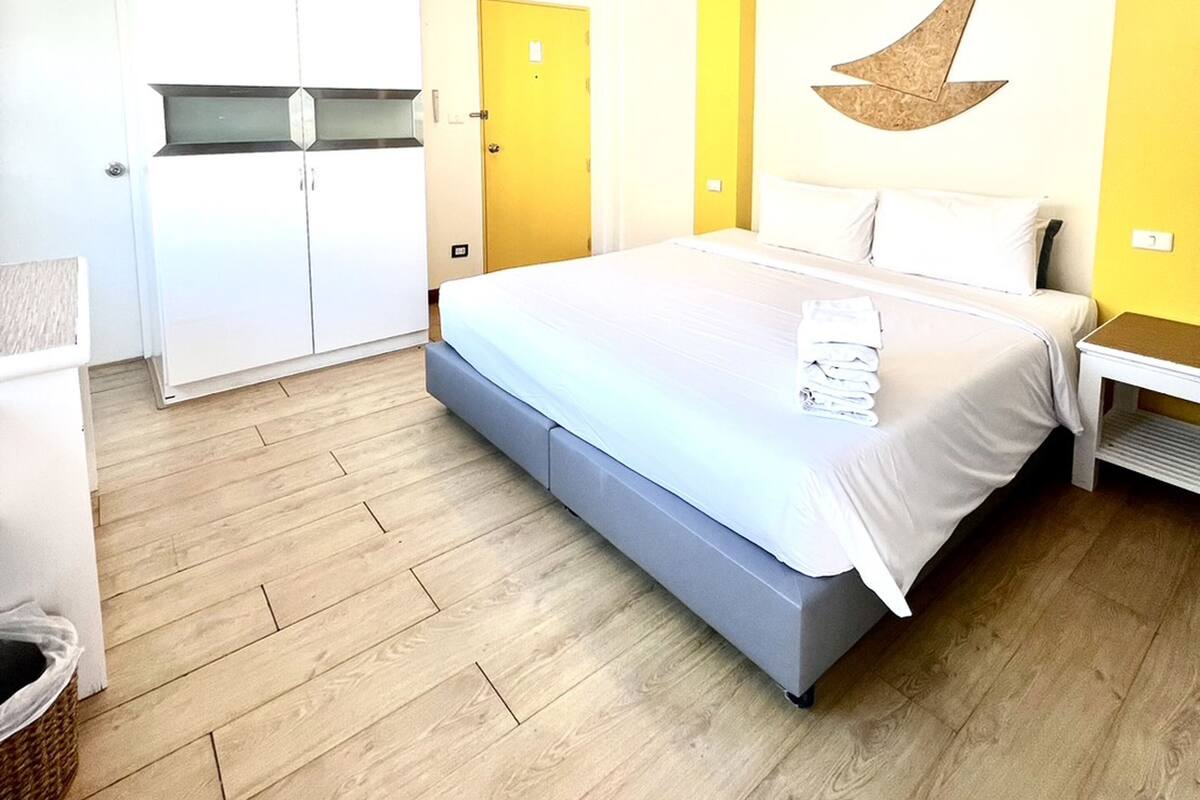 A bedroom with a bed, a wardrobe, and a yellow accent wall.