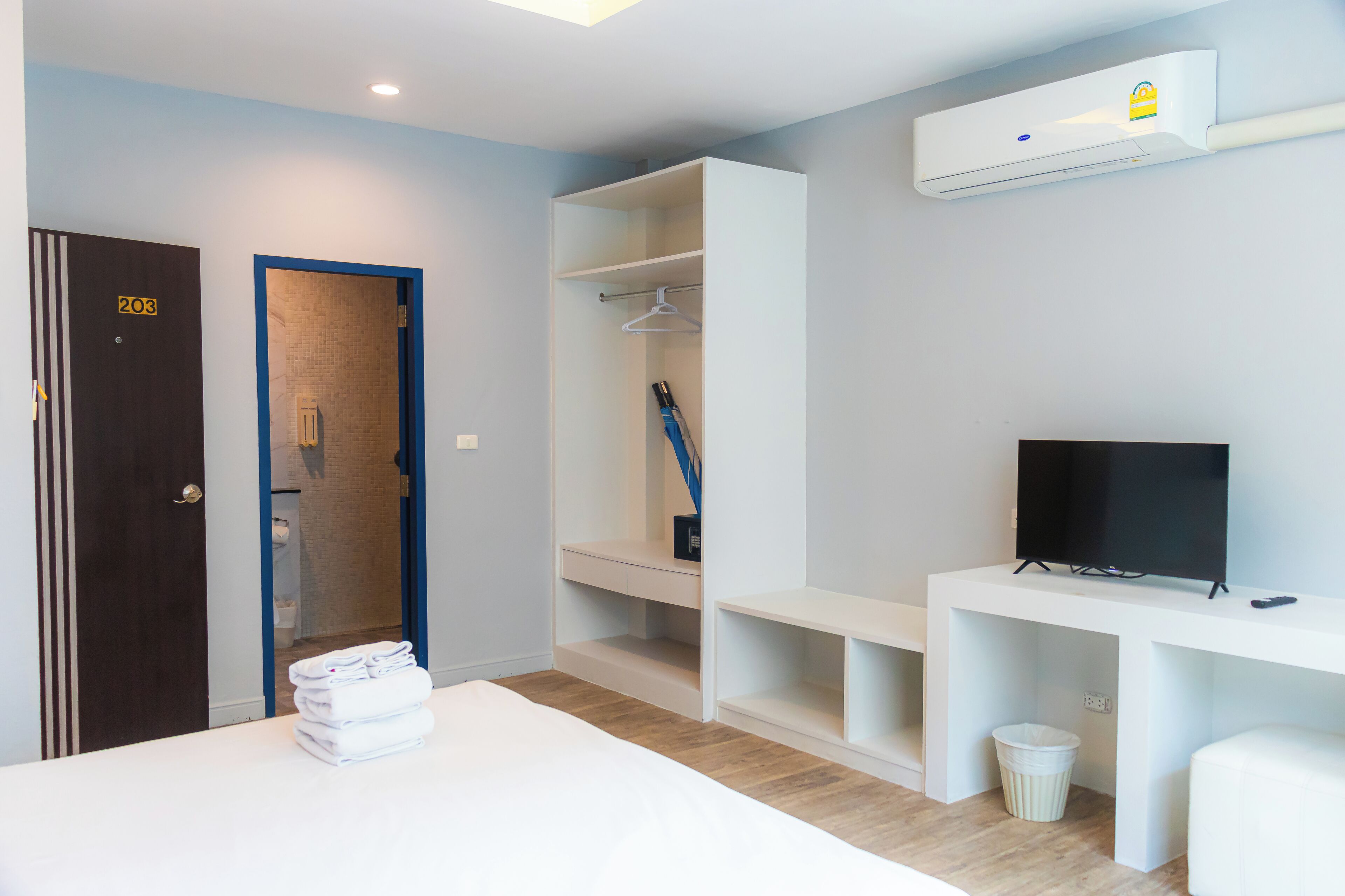 A hotel room with a bed, a TV, a wardrobe, and a bathroom visible through an open door.