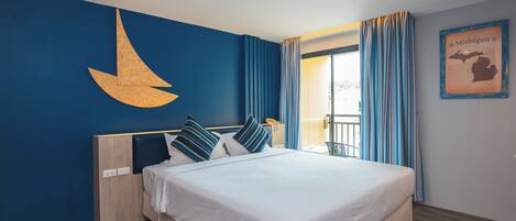 Une chambre d’hôtel avec un grand lit, une tête de lit en bois, une décoration murale en forme de croissant de lune, une carte du Michigan encadrée et un balcon avec des rideaux.