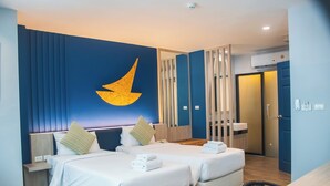 Habitación de hotel con dos camas, una decoración mural grande, un escritorio y un baño visible a través de una puerta.