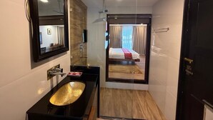 Un baño moderno con un espejo grande, un lavabo negro y una zona de ducha.