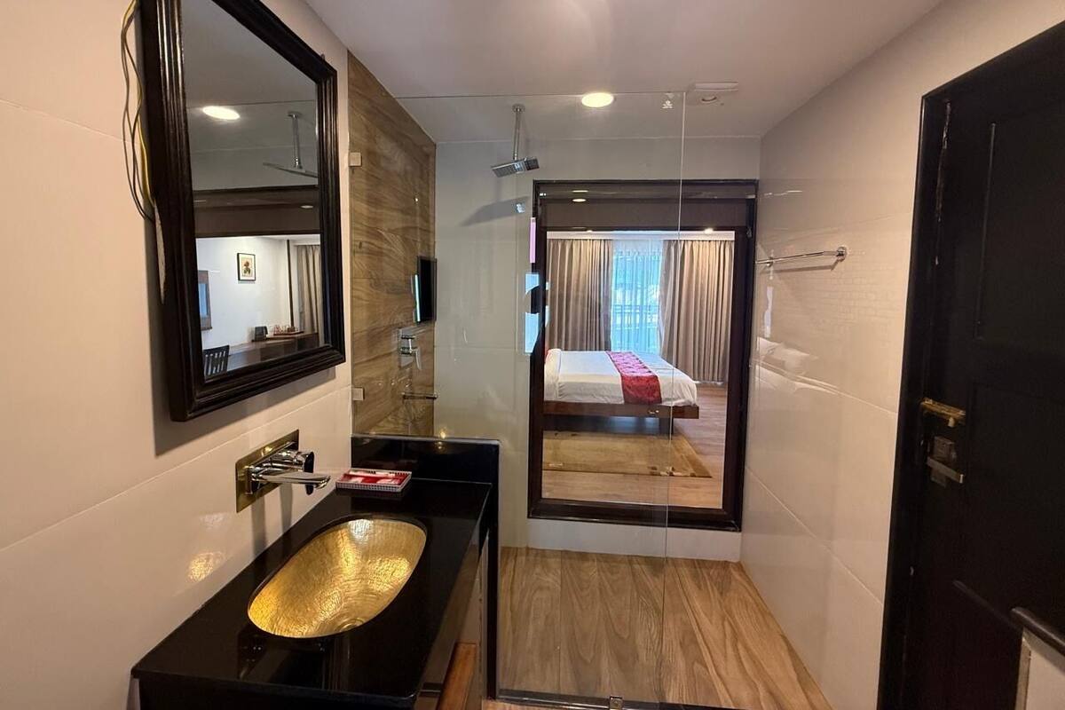 Un baño moderno con un espejo grande, un lavabo negro y una zona de ducha.