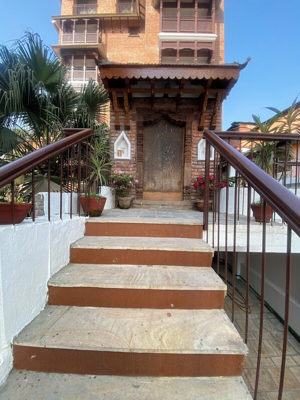 Un escalier menant à un bâtiment traditionnel, doté d’une entrée décorative et agrémenté de plantes en pot.