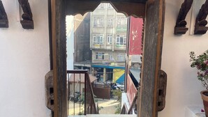 Una puerta de madera con un portón de metal que da a un patio con suelo de baldosas y una planta en maceta.