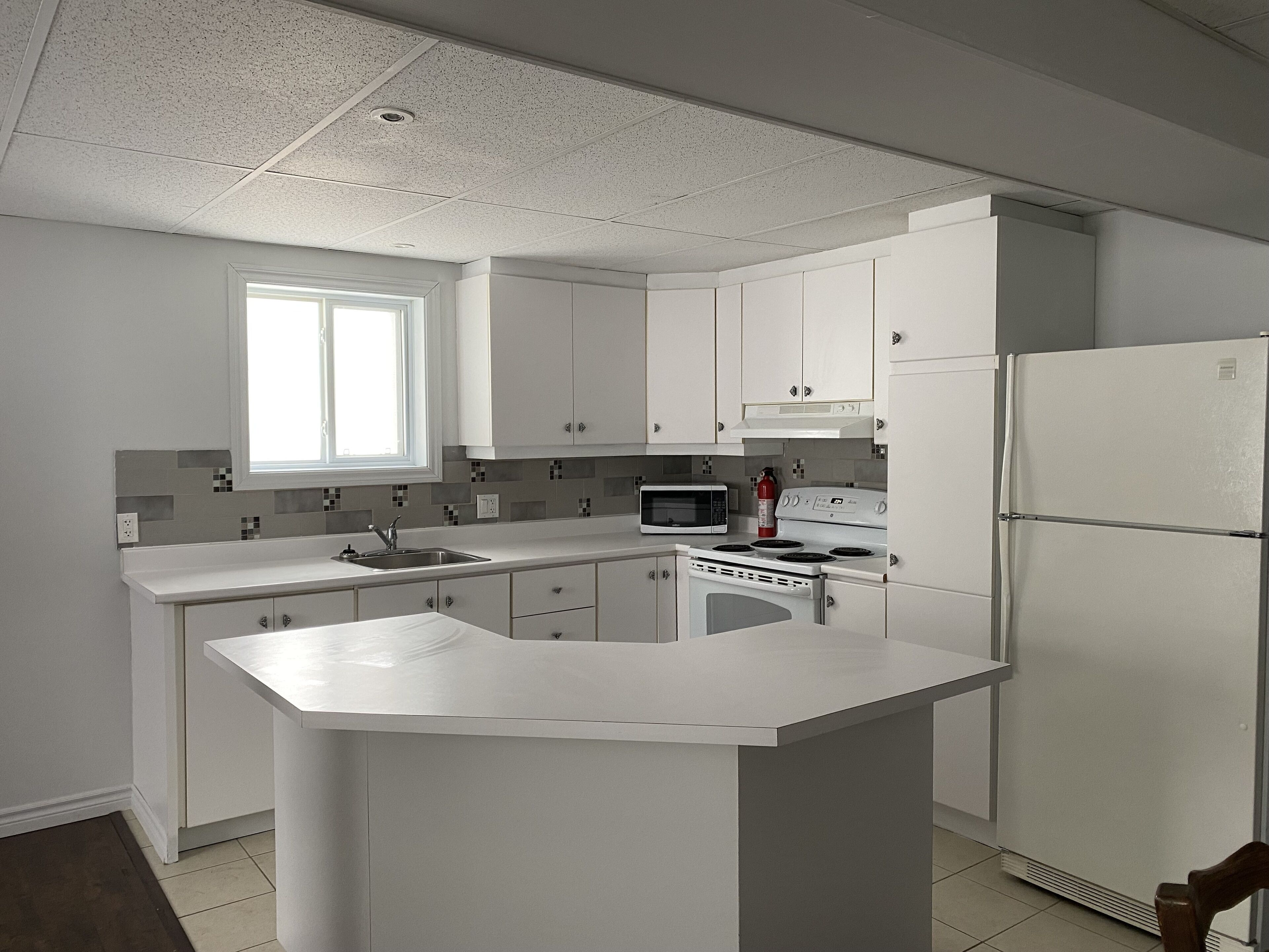 A kitchen with white cabinets, a microwave, stove, and refrigerator.