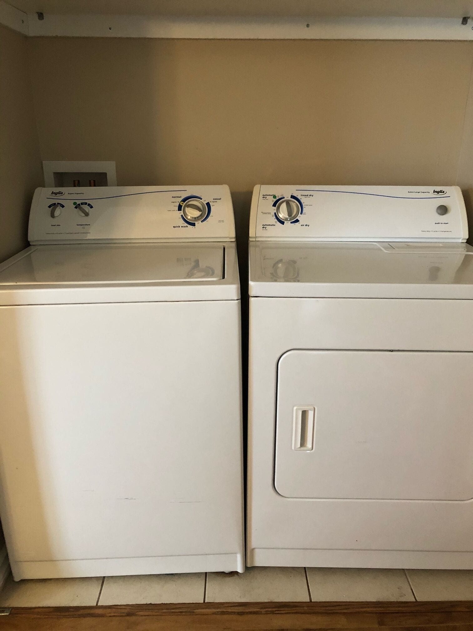 Two front-loading washing machines side by side in a laundry room with a tiled floor.