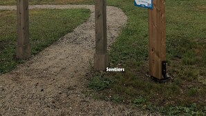 Una estructura de pérgola de madera con señales que indican lugares cercanos y distancias.