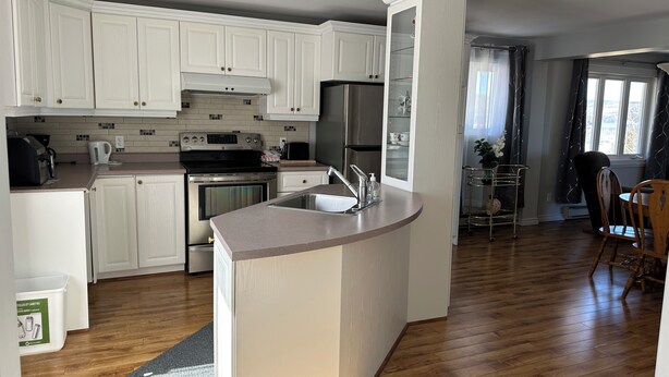 Una cocina moderna con armarios blancos, electrodomésticos de acero inoxidable y una isla central con un lavamanos.