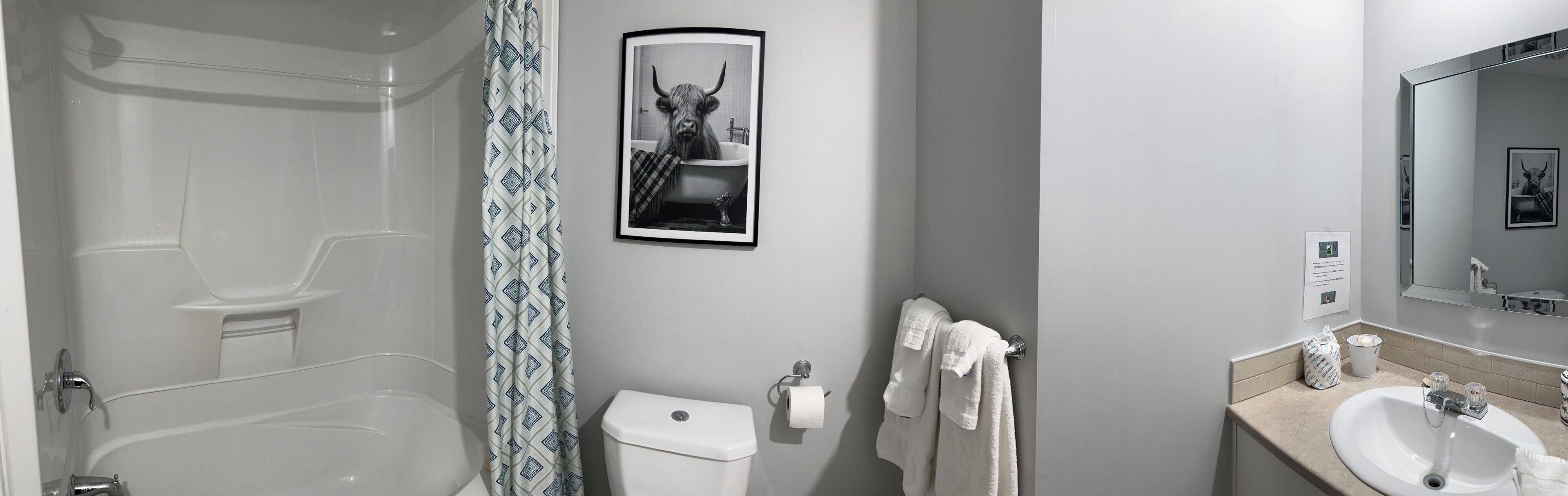 A bathroom with a bathtub, toilet, and sink, with a towel rack and a framed picture on the wall.