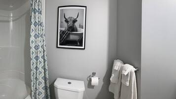 A bathroom with a bathtub, toilet, and sink, with a towel rack and a framed picture on the wall.