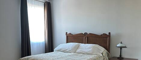 Un dormitorio con cama de madera, mesita de noche, lámpara y ventilador de techo.