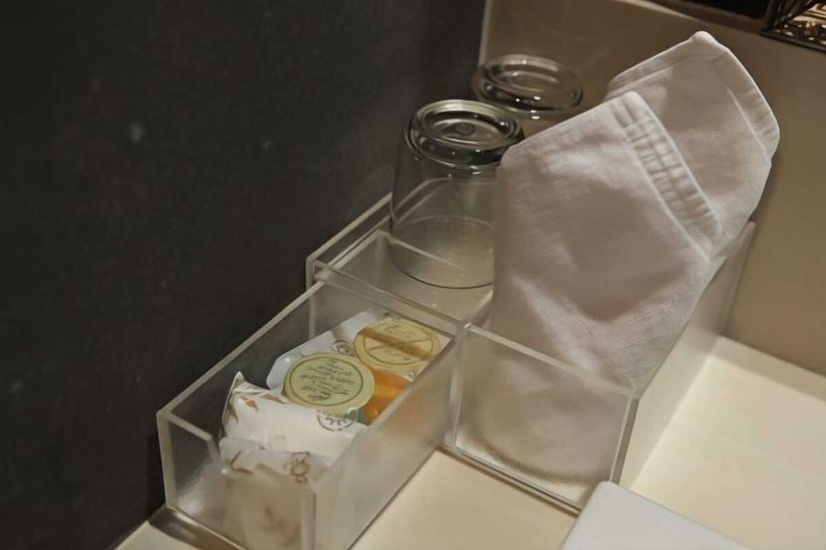A bathroom with a clear storage box containing toiletries, a towel, and a glass container.