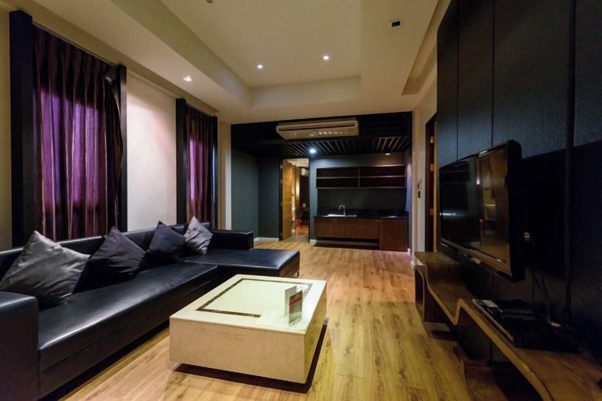 A modern living room with a dark-colored sofa, a wooden coffee table, and a flat-screen TV mounted on the wall.
