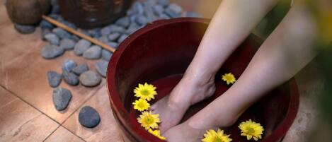 Un baño de pies con flores y piedras.