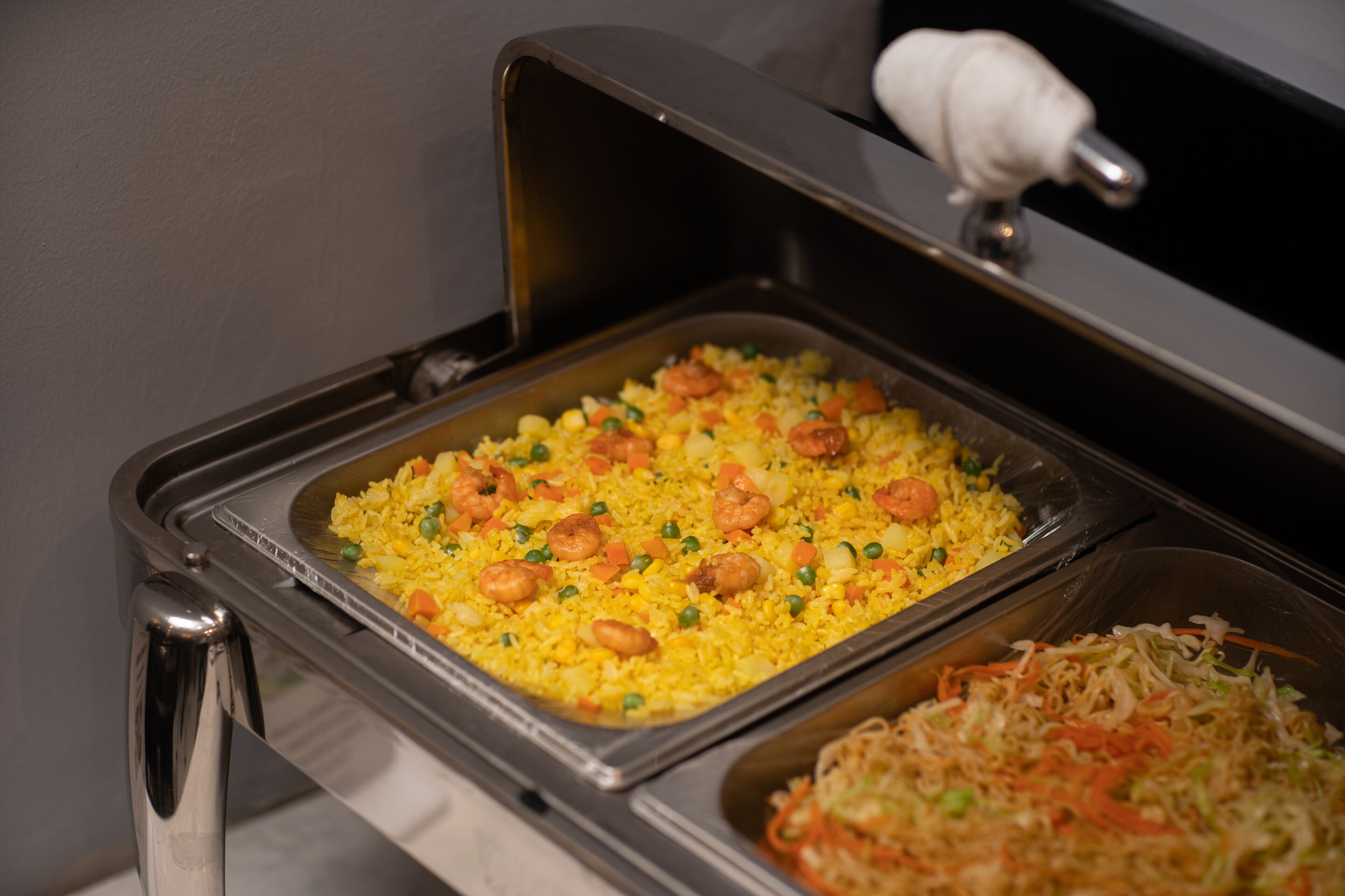Ein Buffet mit gelbem Reis, Erbsen, Karotten und Garnelen.
