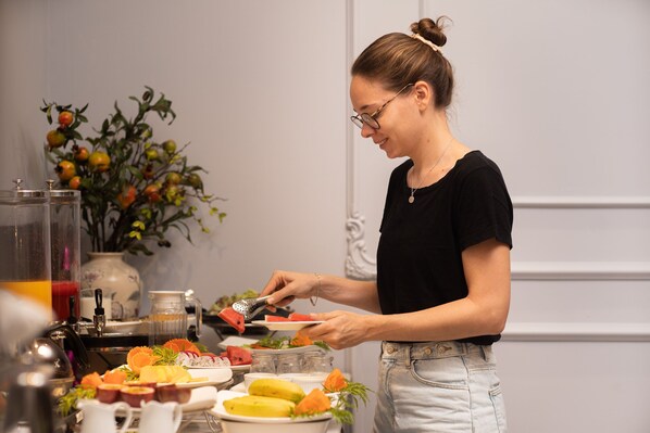 A person serving food at a buffet with various dishes and a decorative plant in the background. - Hanoi Garden Hotel & Spa (Hanoi)