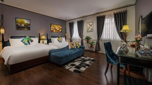 Habitación de hotel con una cama grande, un sofá, una mesa de comedor y un televisor.
