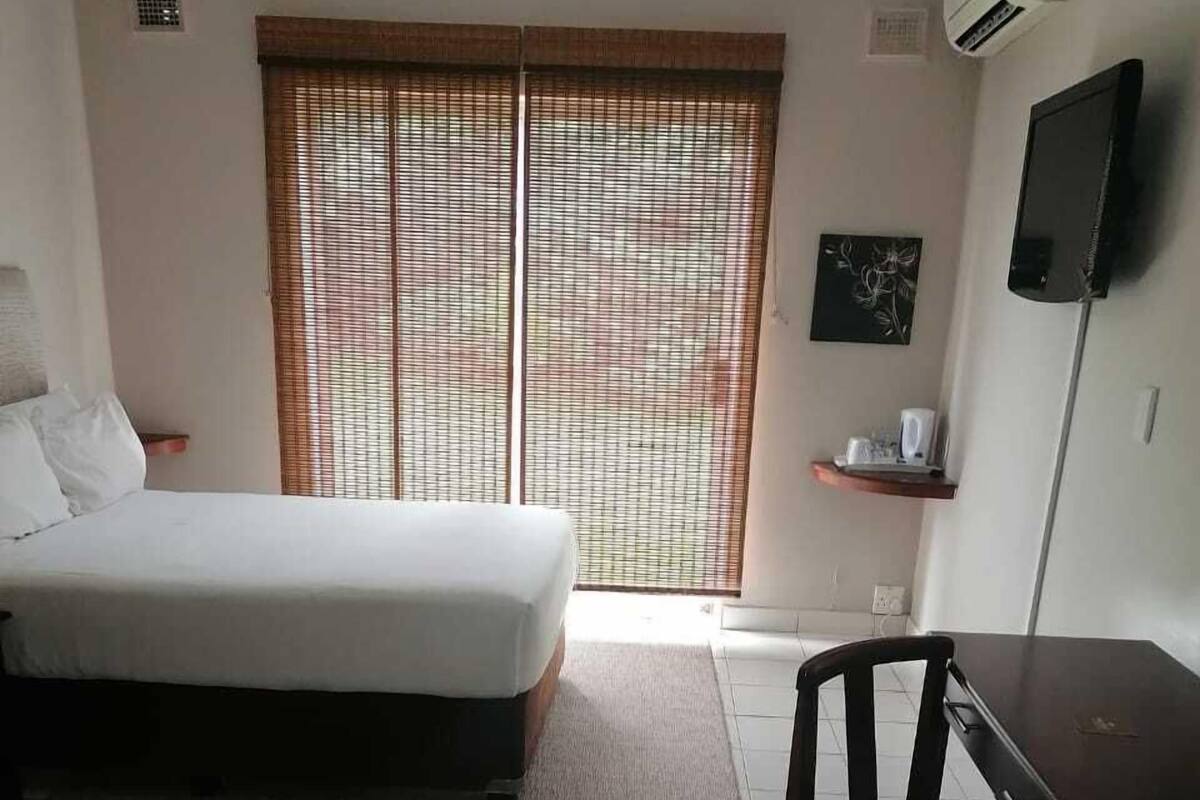 A bedroom with a bed, a desk, and a chair.
