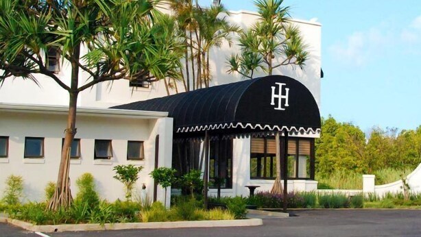 Un hotel amb un disseny modern, amb un logo de la lletra 'H' ben visible a la marquesina de l'entrada.