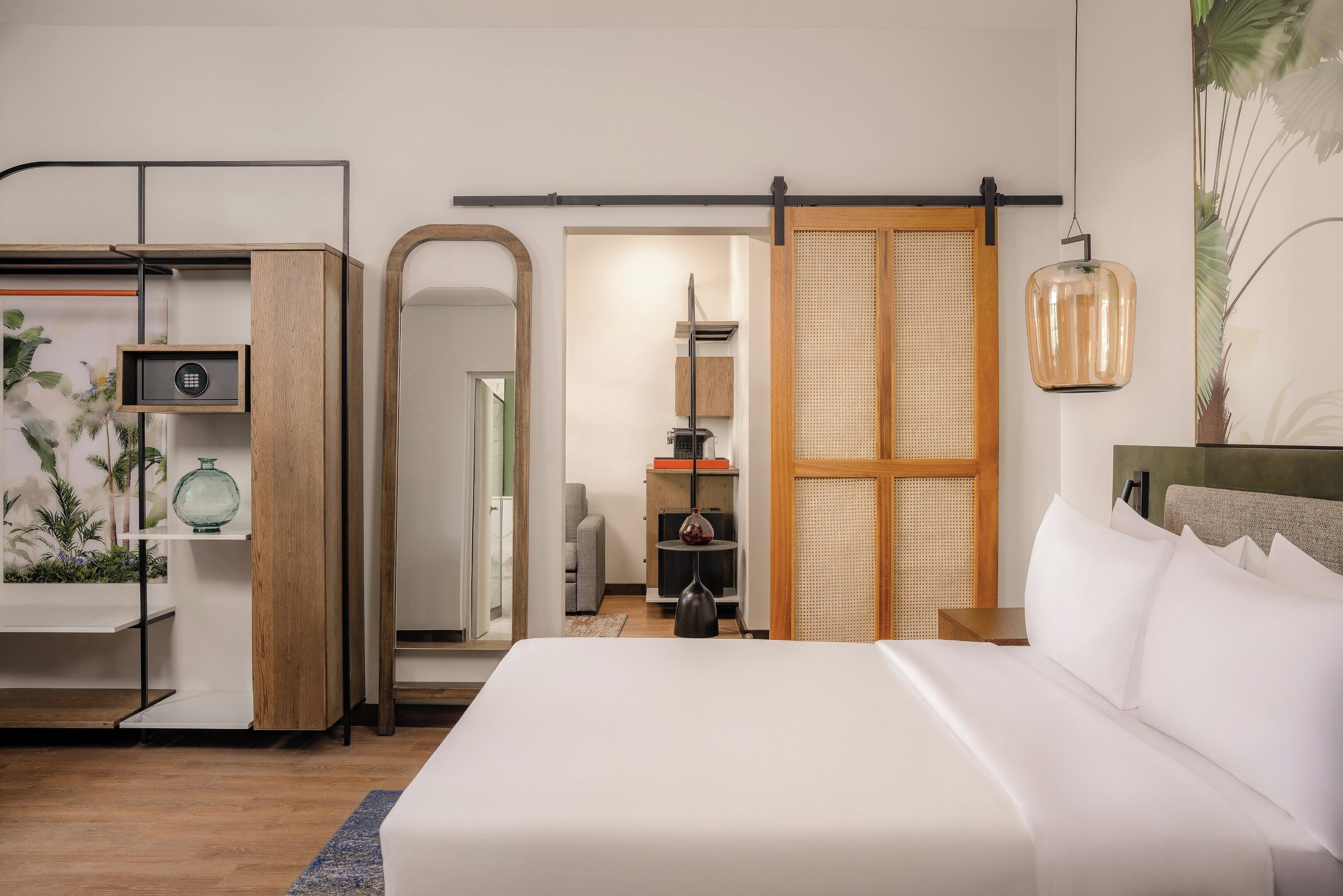 A modern bedroom with a large bed, a wooden wardrobe, a mirror, and a hanging light fixture.
